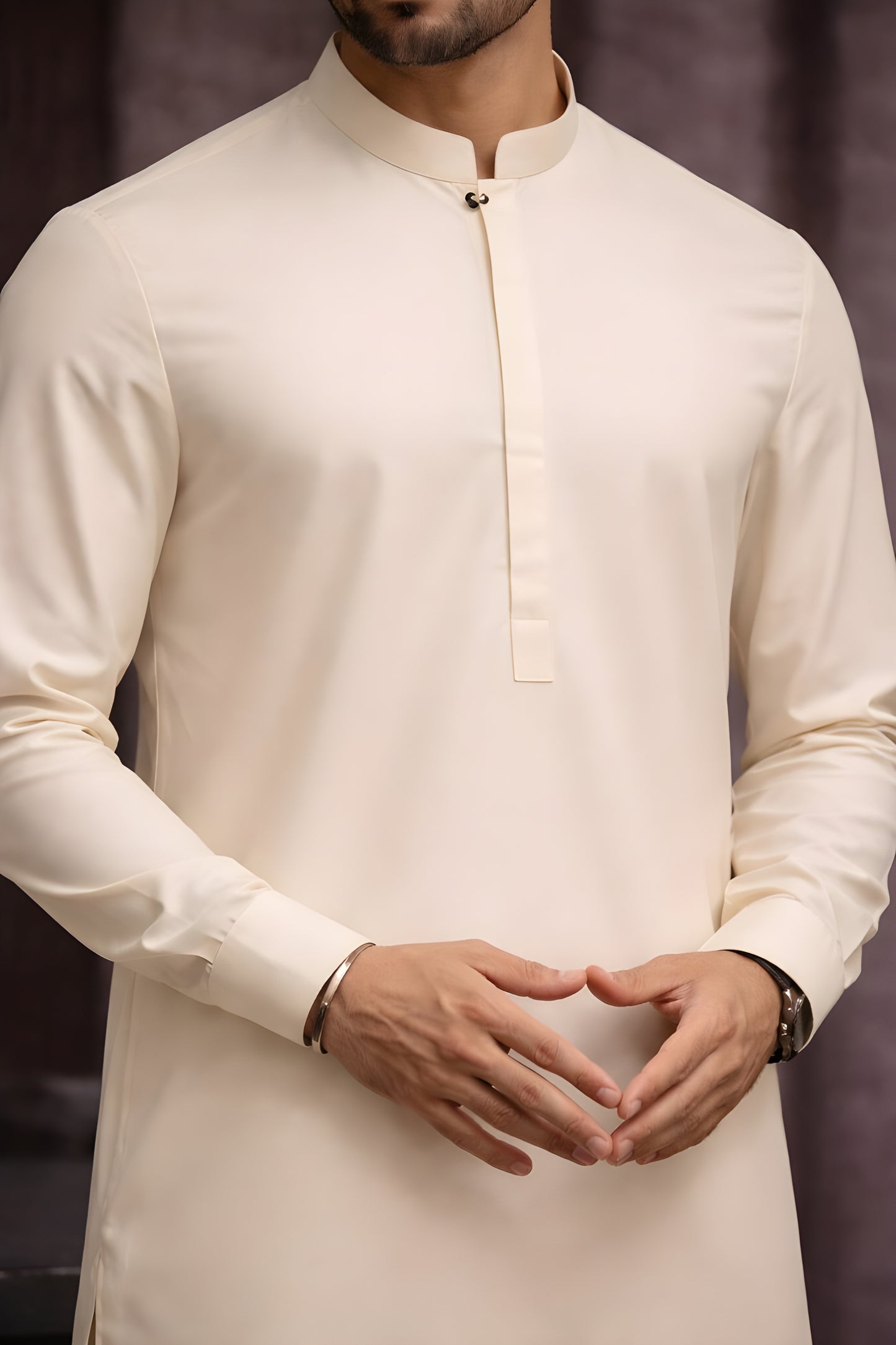 Man wearing a cream kurta with a plain background